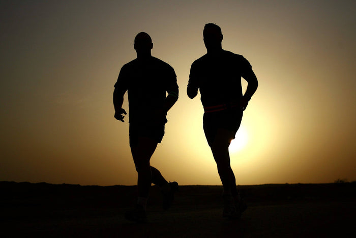 Two men wearing running toe socks running outdoors at sunrise